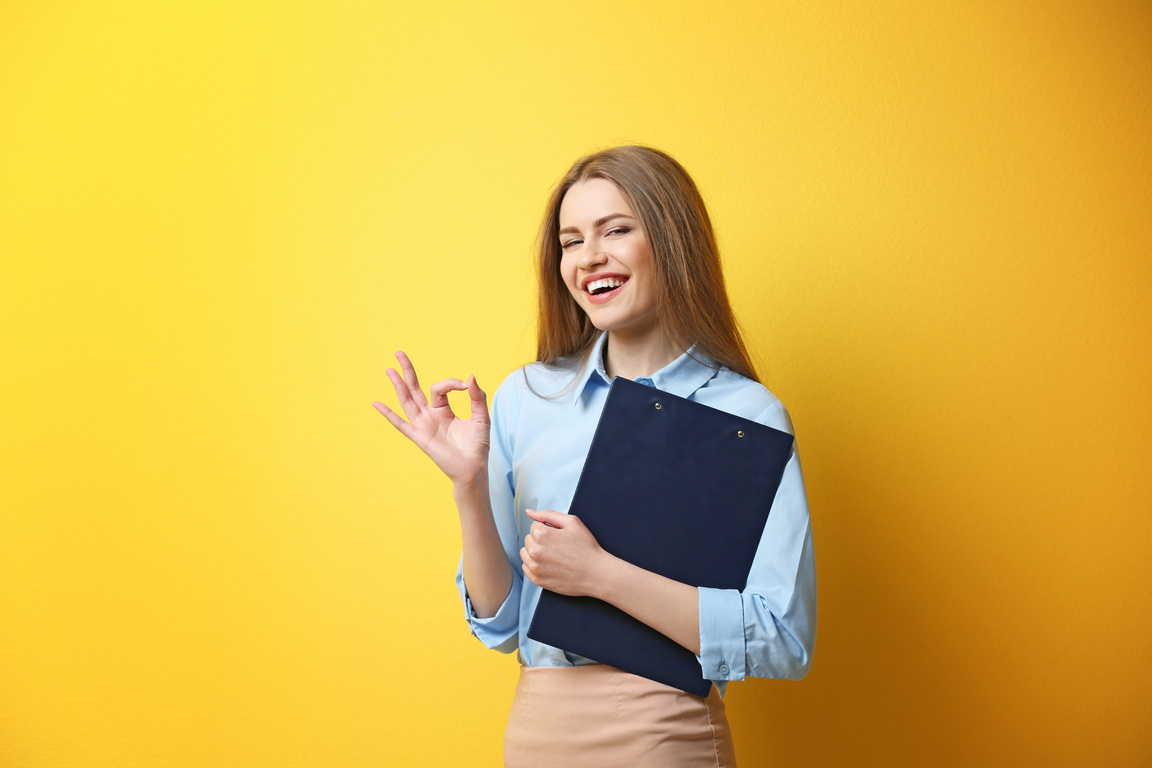 Young Woman Posing with Clipboard on Yellow Background
